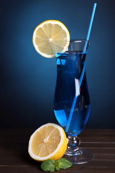 Glass of cocktail on table on dark blue background — Stock Photo, Image