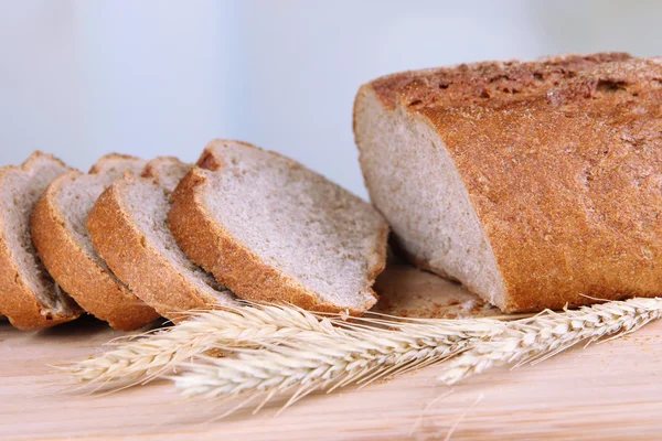 Pane affettato su tavola di legno su sfondo brillante — Foto Stock