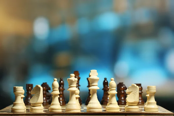 Šachové figurky na palubě na světlé pozadí — Stock fotografie