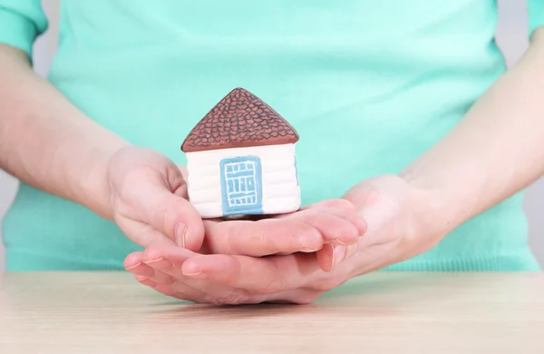 Lilla papper huset i hand närbild, på ljus bakgrund — Stockfoto