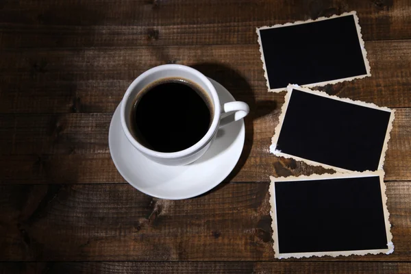 Šálek kávy a prázdné fotografie, na dřevěné pozadí — Stock fotografie