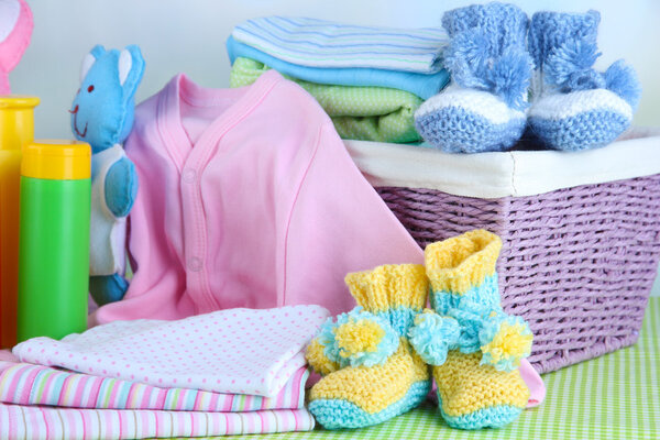 Куча детской одежды в корзине, на столе на цветном фоне
