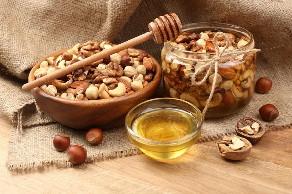 Sweet honey and different nuts on wooden table — Stock Photo, Image