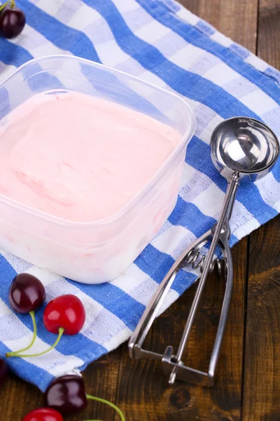 Helado en recipiente y cuchara de helado en mesa de madera de primer plano —  Fotos de Stock