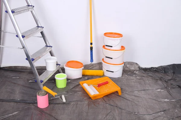 Cubos con pintura y escalera sobre fondo de pared. Foto conceptual de los trabajos de reparación en la habitación — Foto de Stock