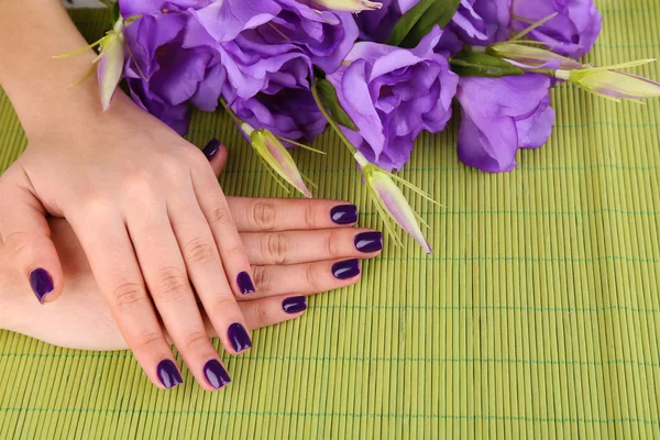 Beautiful woman hands with flowers on bamboo background — Stock Photo, Image