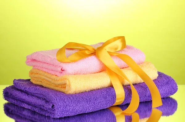 Colorful towels with ribbon on green background — Stock Photo, Image