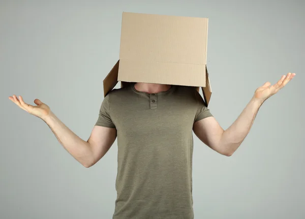 Uomo con scatola di cartone sulla testa su sfondo grigio — Foto Stock
