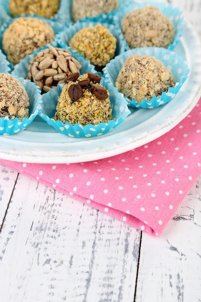 Set of chocolate candies, on plate, on wooden background — Stock Photo, Image