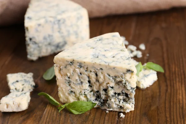 Queijo azul saboroso com manjericão, na mesa de madeira — Fotografia de Stock