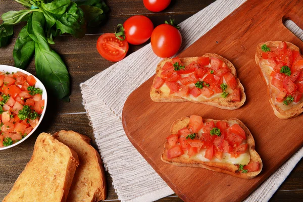 Delicioso bruschetta com tomates em corte placa close-up — Fotografia de Stock