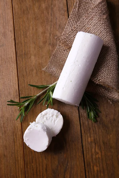 Tasty bushe cheese with rosemary, on wooden table — Stock Photo, Image