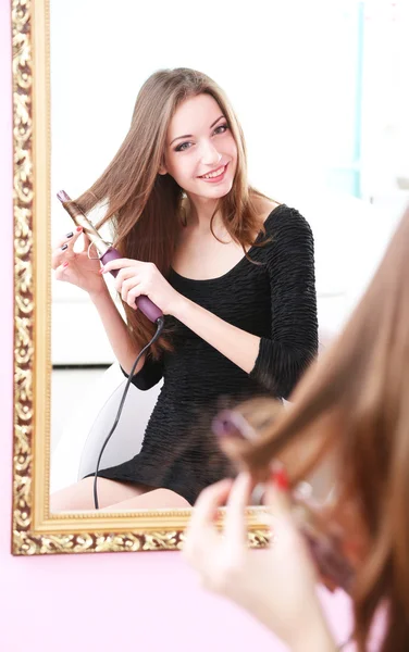 Unga vackra kvinnan att göra frisyr nära spegel — Stockfoto
