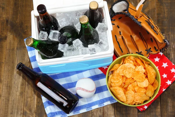 Ice chest full of drinks in bottles on color napkin, on wooden background — Stock Photo, Image