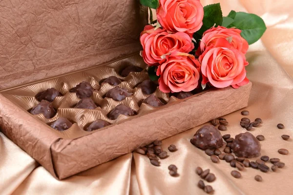 Heerlijke chocolade in doos met bloemen op gouden achtergrond — Stockfoto