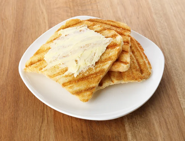 Gegrild brood met boter op houten tafel — Stockfoto