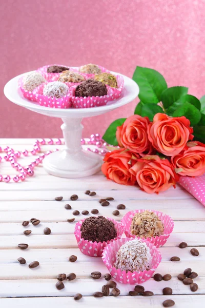 Conjunto de bombones de chocolate sobre mesa sobre fondo rosa —  Fotos de Stock