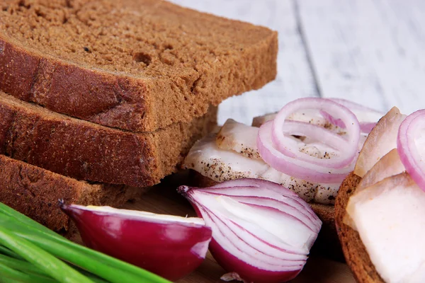 Slices of bread and lard with onion on cutting board close up — Stock Photo, Image