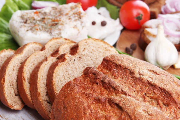 Sneetjes brood en reuzel met groenten op tafel close-up — Stockfoto