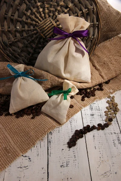 Säcke mit Kaffee auf Holztisch, auf Sacktuchhintergrund — Stockfoto