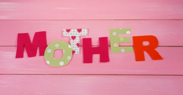 Mother- lettering of handmade paper letters on pink wooden background — Stock Photo, Image