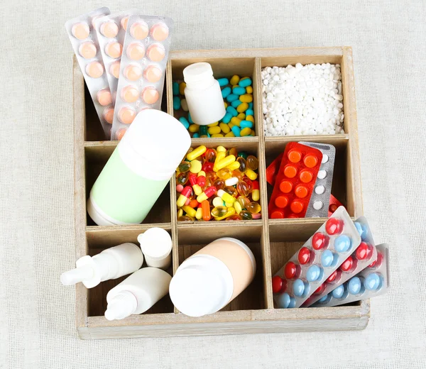 Medicinska piller, ampuller i trälåda, på färgbakgrund — Stockfoto