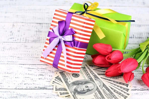 Geschenkdozen met geld en bloemen op een houten achtergrond kleur — Stockfoto