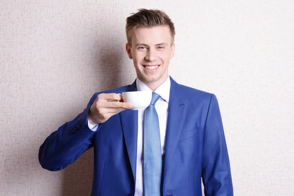 Портрет бізнесмена з чашкою кави біля стіни — стокове фото