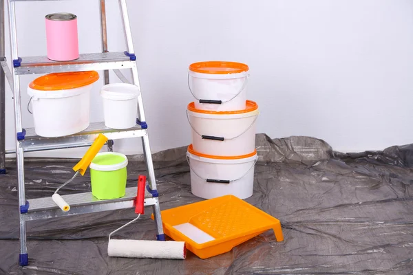 Cubos con pintura y escalera sobre fondo de pared. Foto conceptual de los trabajos de reparación en la habitación — Foto de Stock