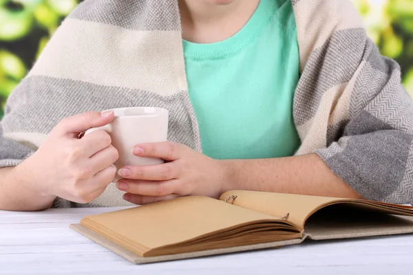 Vrouw leest boek en drinken koffie of thee, close-up — Stockfoto