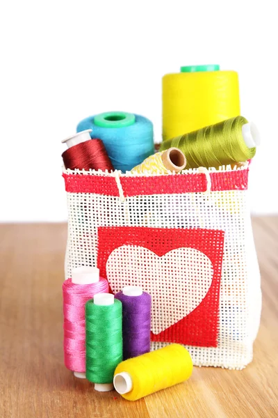 Colorful bobbins of thread  in bag, on wooden  table, on white background — Stock Photo, Image