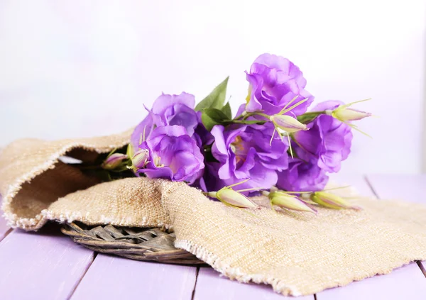 Eustoma artificial roxo em pano de saco na tabela de madeira da cor, no fundo brilhante — Fotografia de Stock