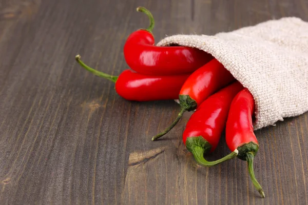 Pimientos rojos picantes en bolsa sobre fondo de madera — Foto de Stock