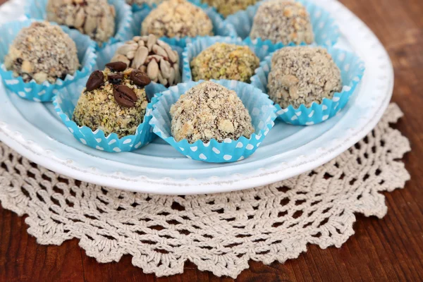 Conjunto de bombones de chocolate, en plato, sobre fondo de madera — Foto de Stock