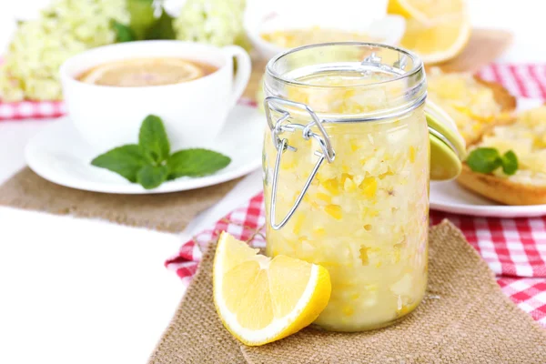 Leckere Zitronenmarmelade mit einer Tasse Tee auf dem Tisch in Großaufnahme — Stockfoto