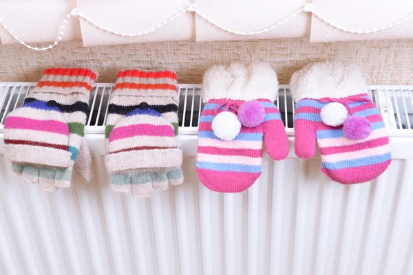 Knitted gloves drying on heating radiator — Stock Photo, Image