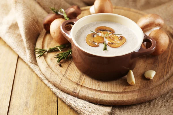 Komposisi dengan sup jamur dalam pot, jamur segar dan kering, di atas meja kayu, di latar belakang kain karung — Stok Foto