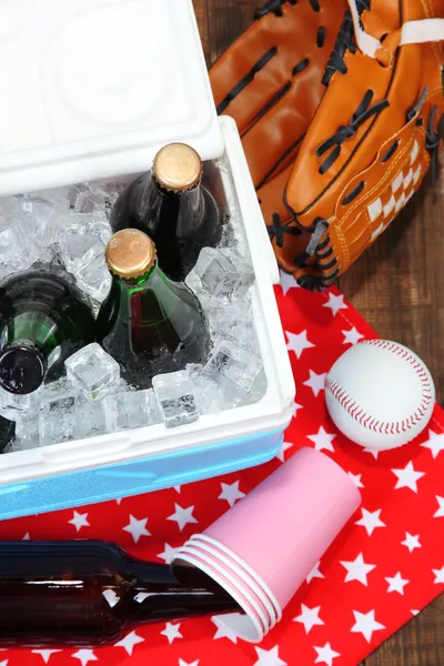 Ice chest full of drinks in bottles on color napkin, on wooden background — Stock Photo, Image