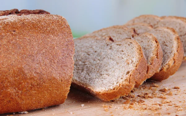 Szeletelt kenyér, fából készült táblán a világos háttér — Stock Fotó