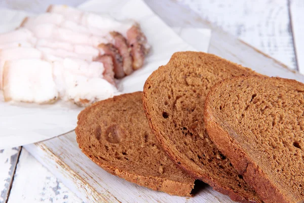 Slices of bread and lard on cutting board on wooden background — Stock Photo, Image