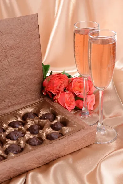 Deliciosos chocolates en caja con flores sobre fondo dorado Imágenes de stock libres de derechos