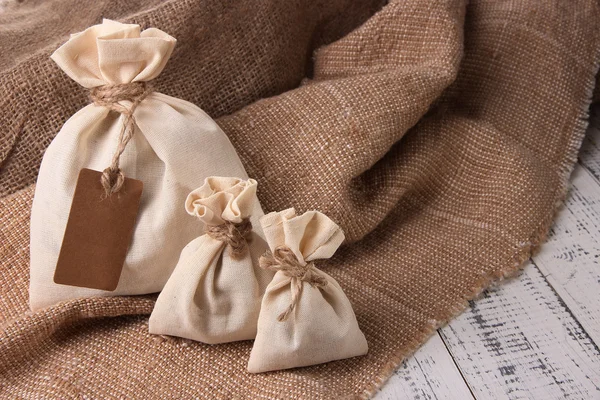 Jute bags on sackcloth, on wooden background — Stock Photo, Image
