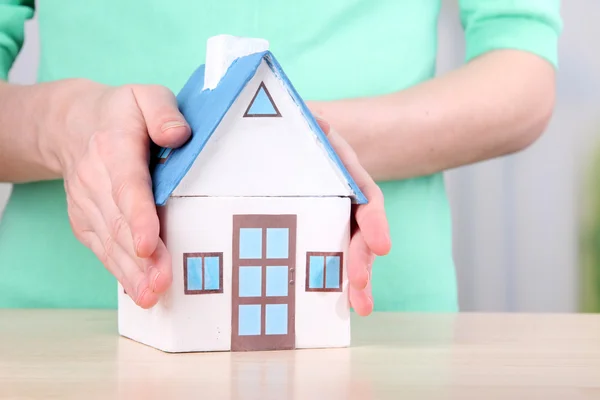 Little paper house in hand close-up, on light background — Stock Photo, Image