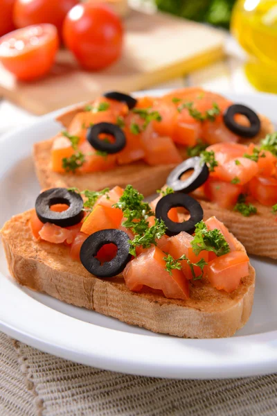 Delicioso bruschetta com tomates no prato na mesa close-up — Fotografia de Stock