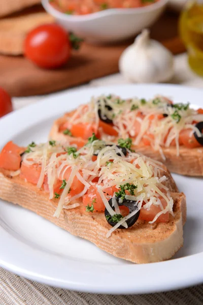 Delicious bruschetta with tomatoes on plate on table close-up — Stock Photo, Image