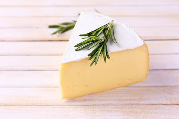 Tasty Camembert cheese with rosemary, on wooden table — Stock Photo, Image