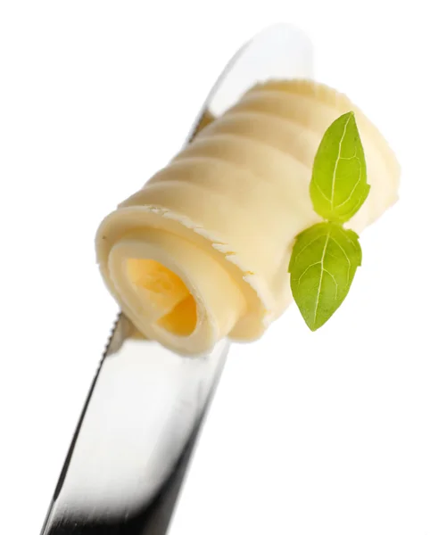 Ricciolo di burro fresco con basilico su coltello, isolato su bianco — Foto Stock