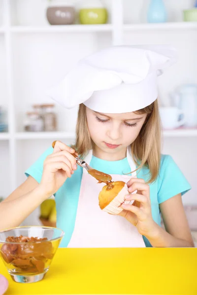 Menina pequena decorando cupcakes na cozinha em casa — Fotografia de Stock