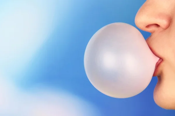 Person doing bubble with chewing gum on bright background — Stock Photo, Image