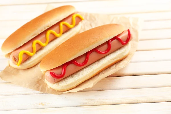 Sabrosos perritos calientes en mesa de madera — Foto de Stock